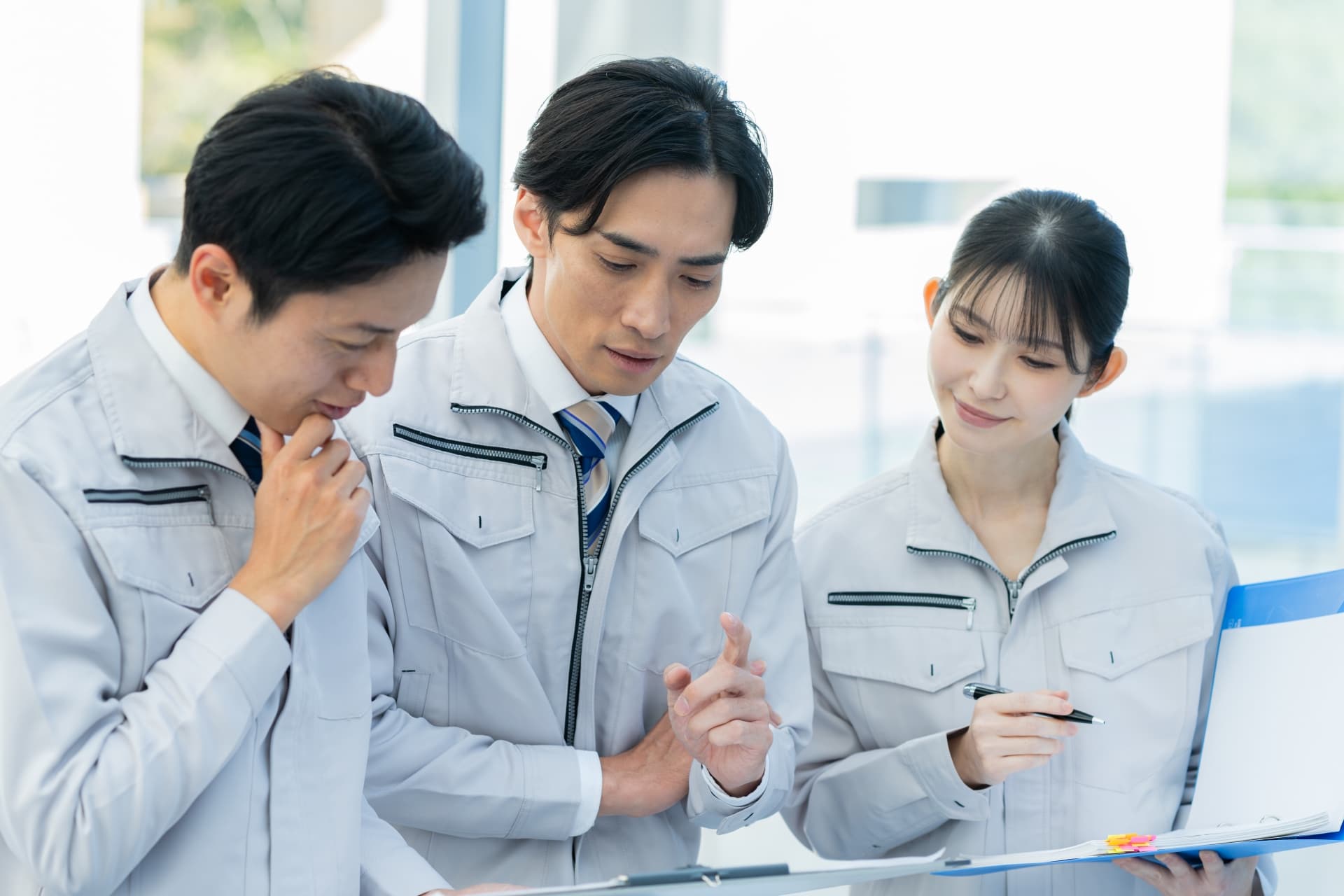 ミーティングをする作業服を着た男女三人